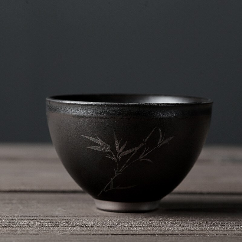 Beschrijving van een zwarte theekop van aardewerk, een zilveren retro theekopje, een zen theekopje, een middelgrote theeset met een kop en een pin-cha-bei.: Bamboe geluksbekertje