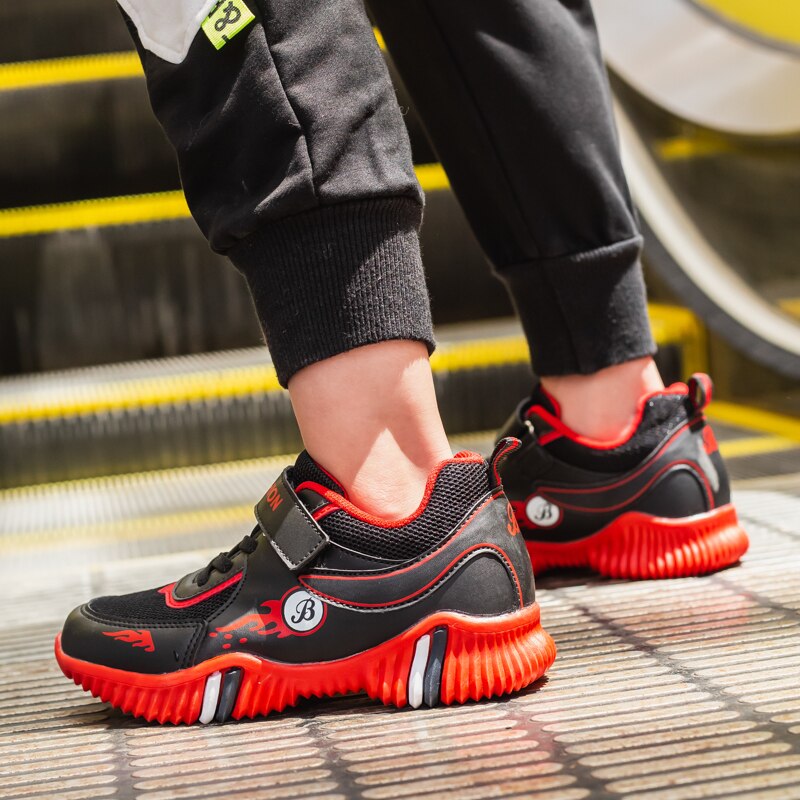 A child wearing black and red sneakers on an escalator