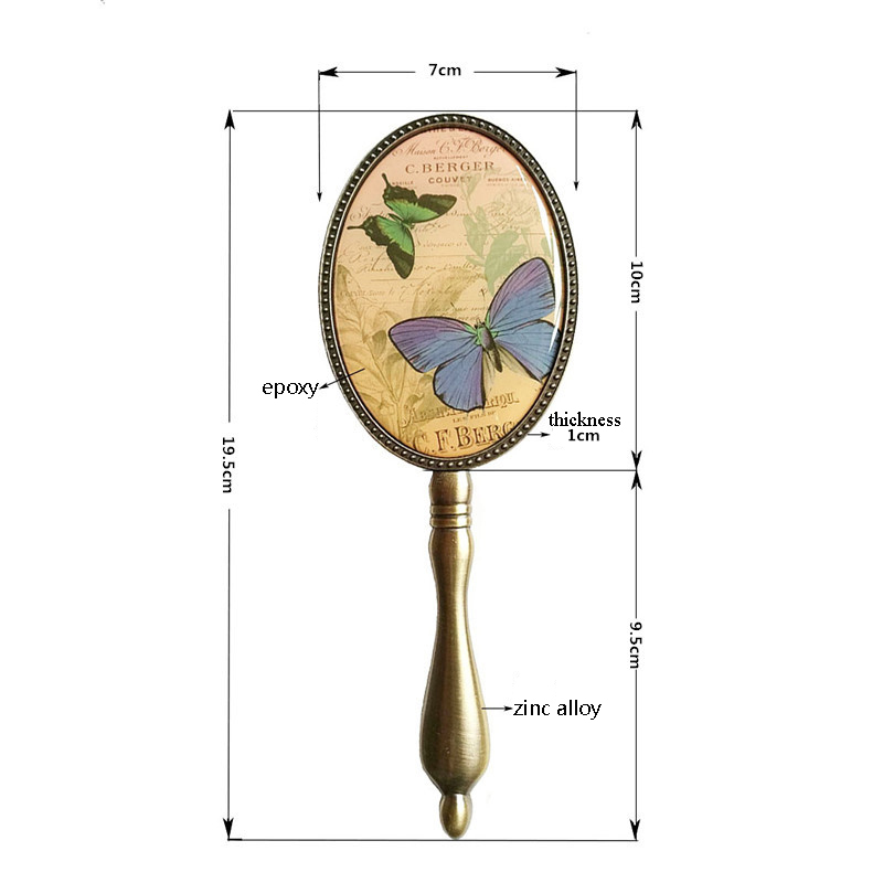 Europeisk vintage antik mässing oval 3 x 4 tum metalllegerad inramad glashandspegel med fjäril epoxidekor bak