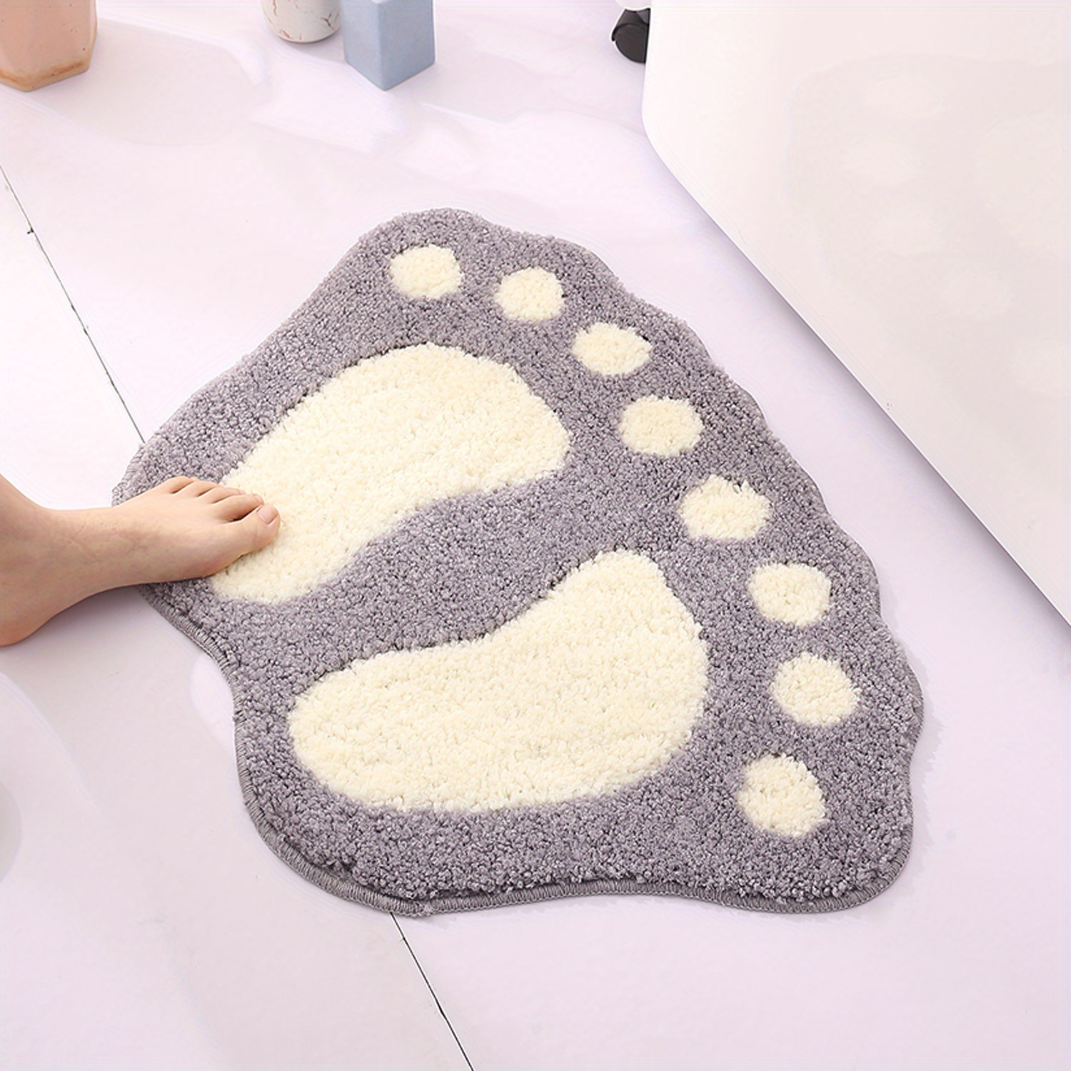 Un petit tapis mignon, moelleux et lavable en machine avec des empreintes. Il peut être utilisé comme tapis antidérapant dans la salle de bain.